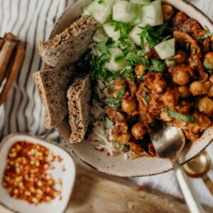 Delicious vegan bowl of chickpeas, rice, and cucumber, garnished with fresh herbs and spices.